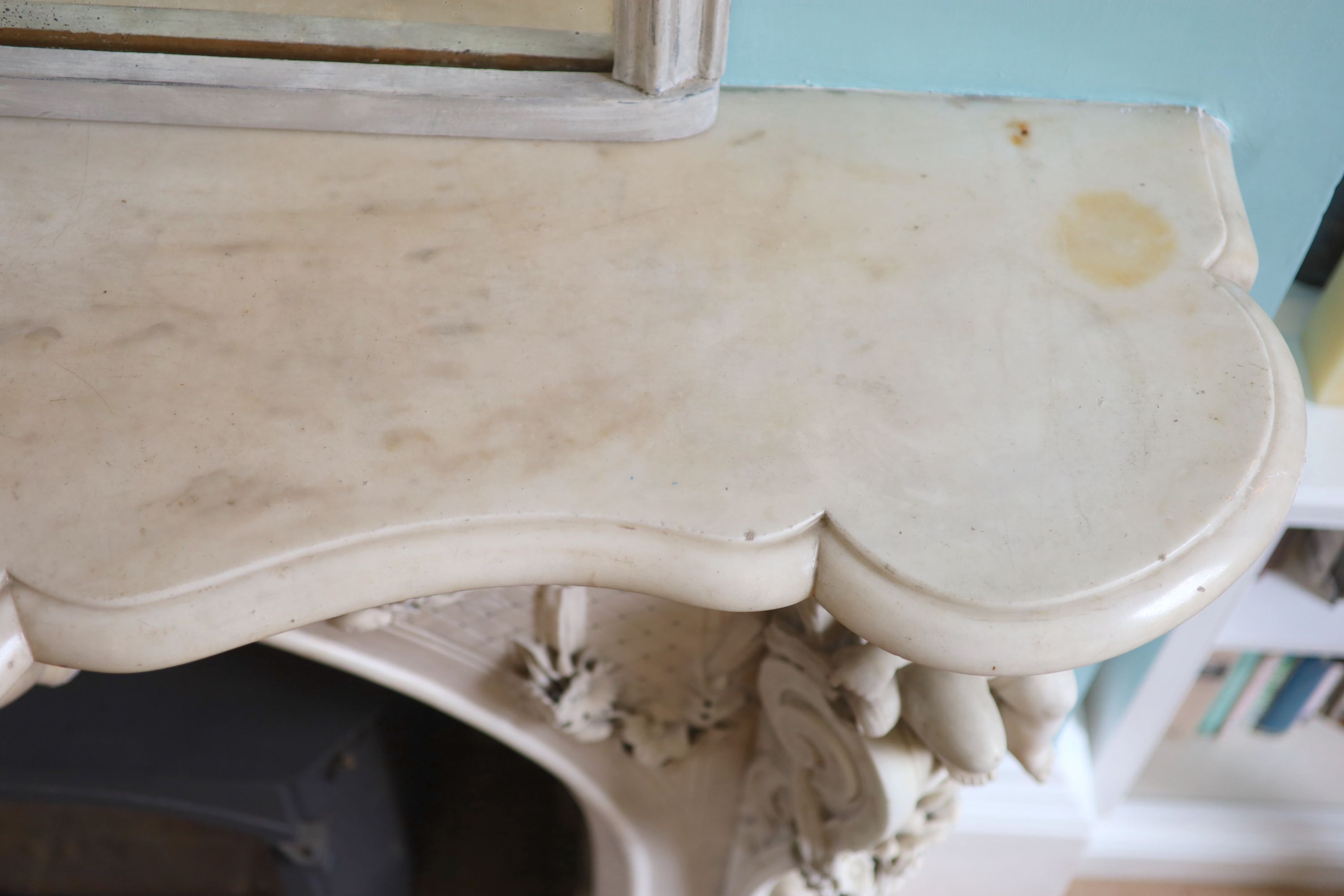 An important mid 19th century Italian white Carrara marble chimney piece, carved in the rococo taste, with seated putti, foliage swags